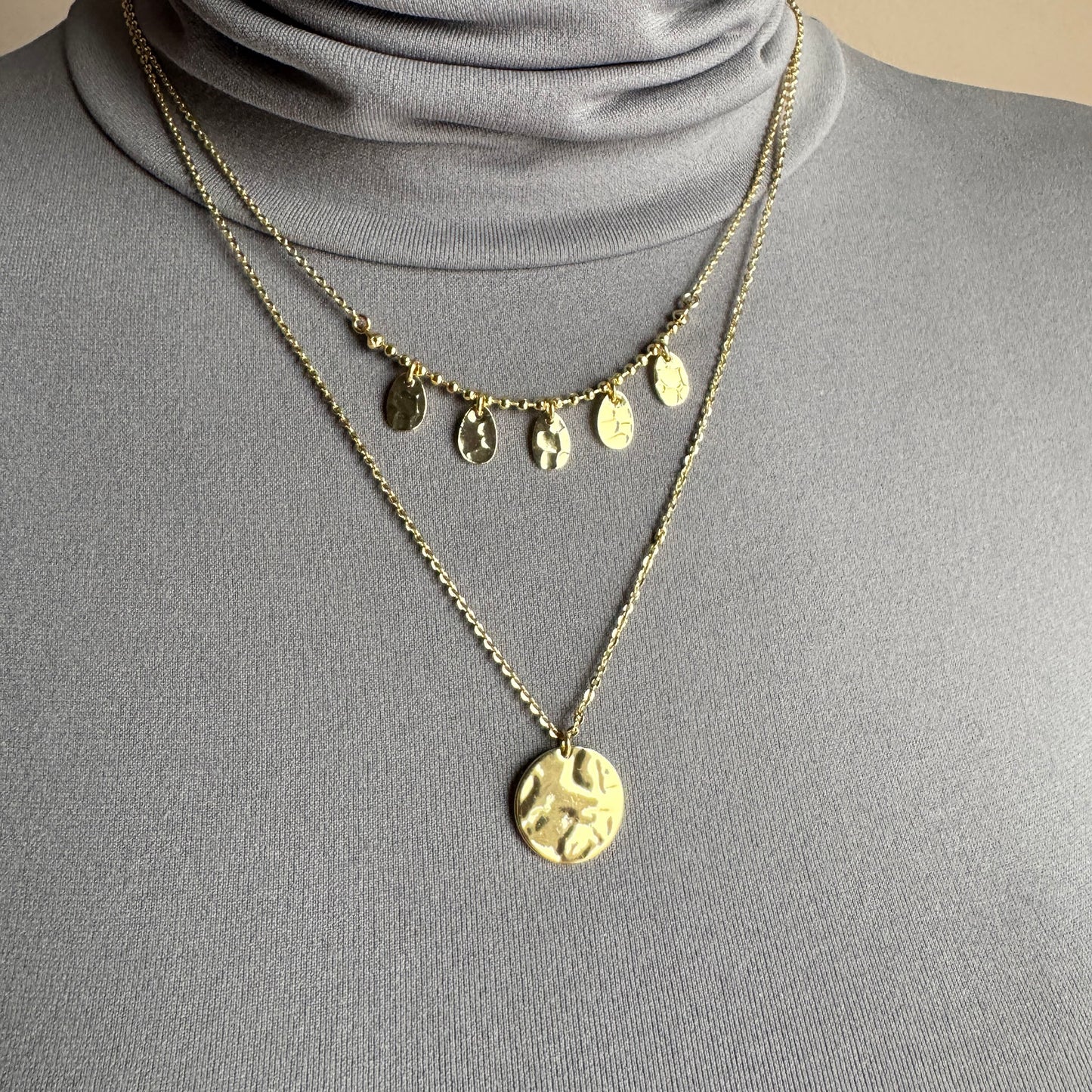 Gold medallion necklace IRL worn layered on the neck with hammered pendants