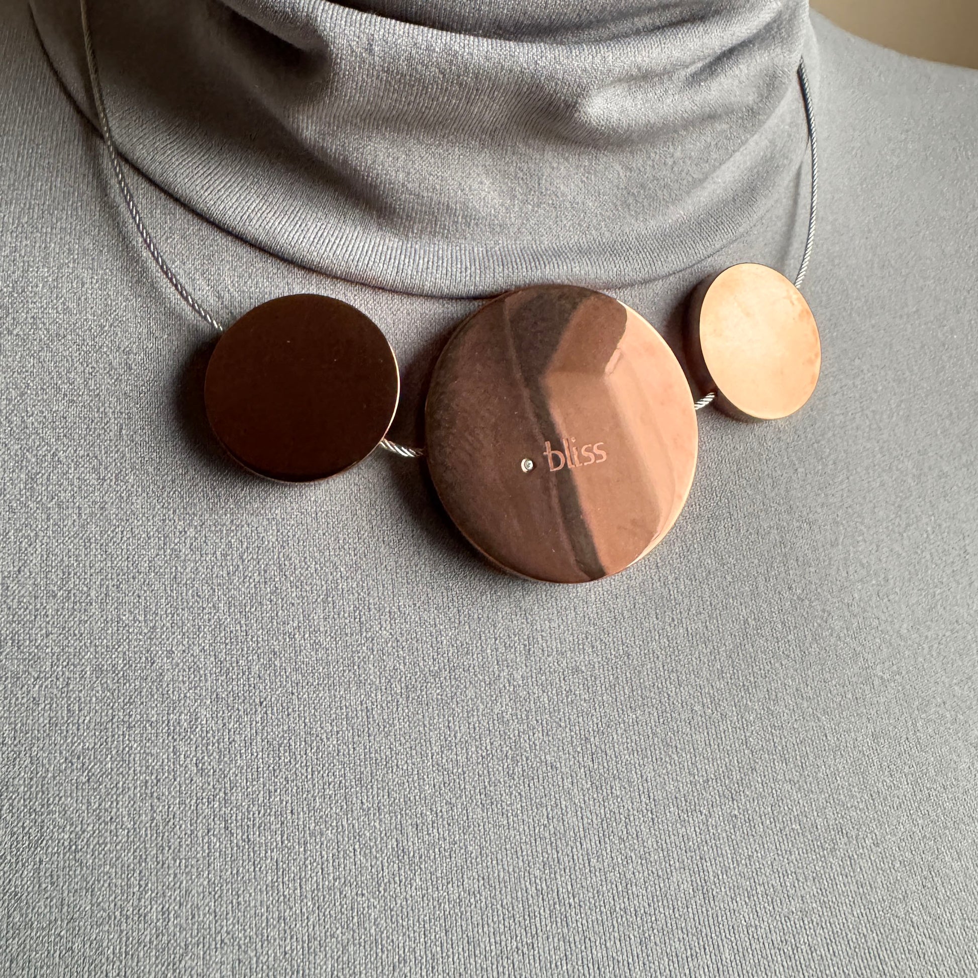 Three medallion necklace worn close to the neck with warm brown discs