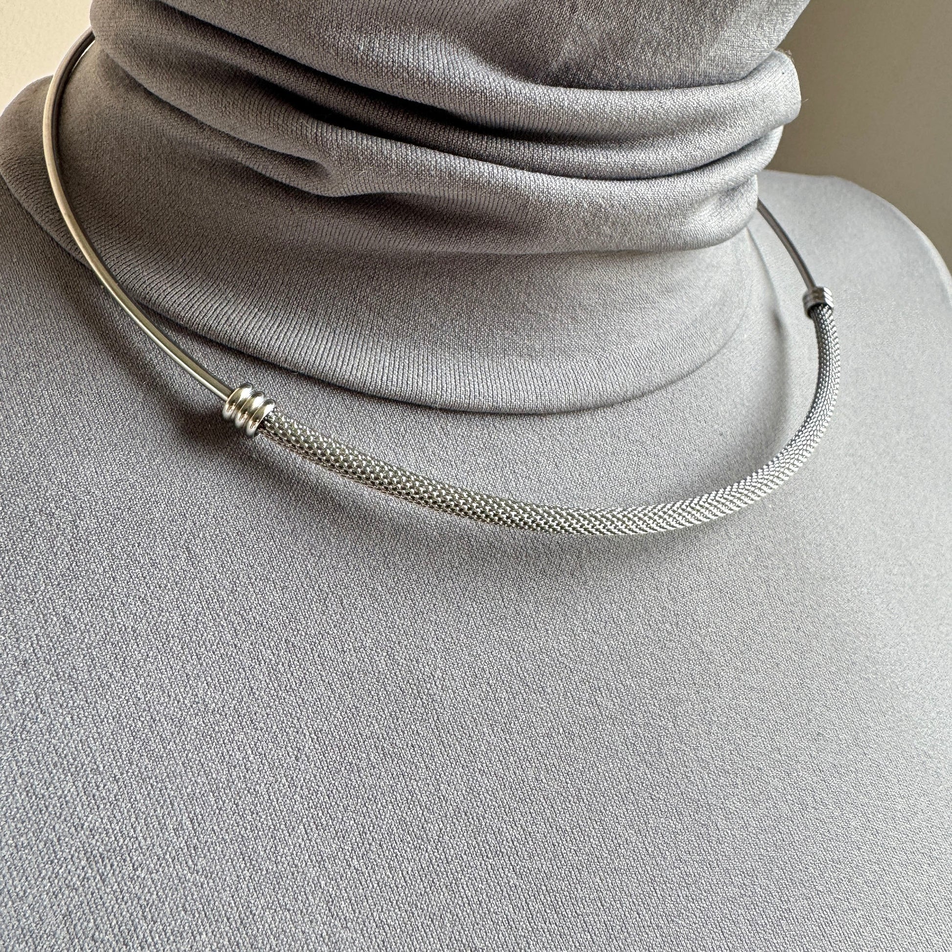 Detalle de collar mesh plateado con brillo sereno y líneas limpias