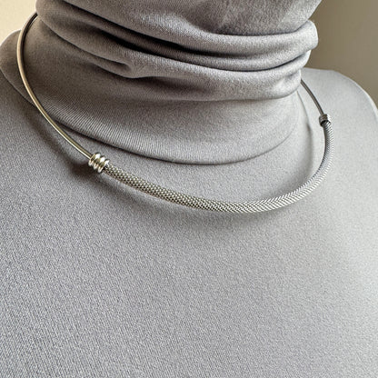 Detalle de collar mesh plateado con brillo sereno y líneas limpias