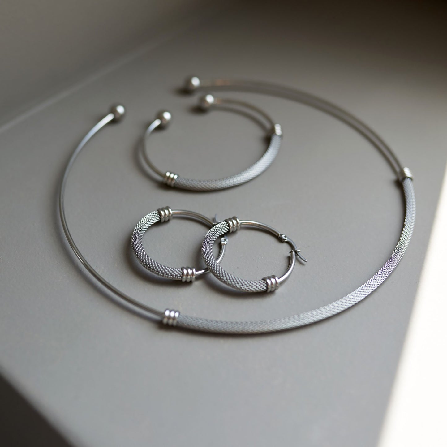 Silver mesh set with open bracelet and hoop earrings on display