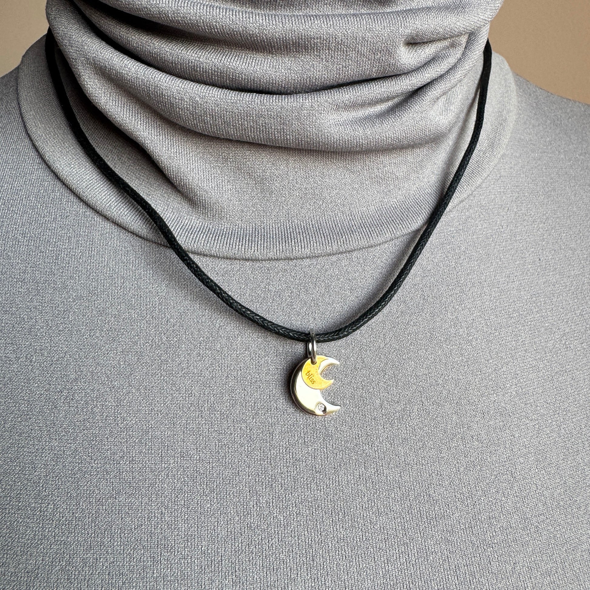 Silver and gold moon pendant worn on an adjustable cord near the collarbone