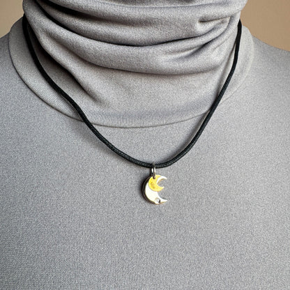 Silver and gold moon pendant worn on an adjustable cord near the collarbone