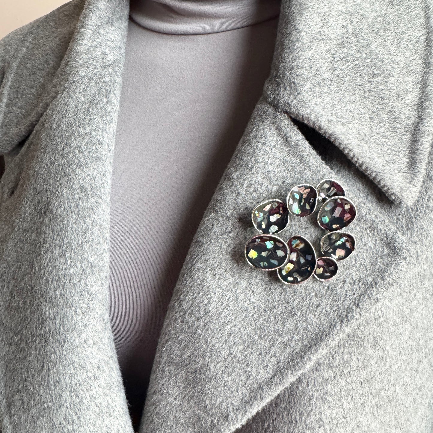 Mother-of-pearl brooch Sonata worn on a coat with a dark glossy surface