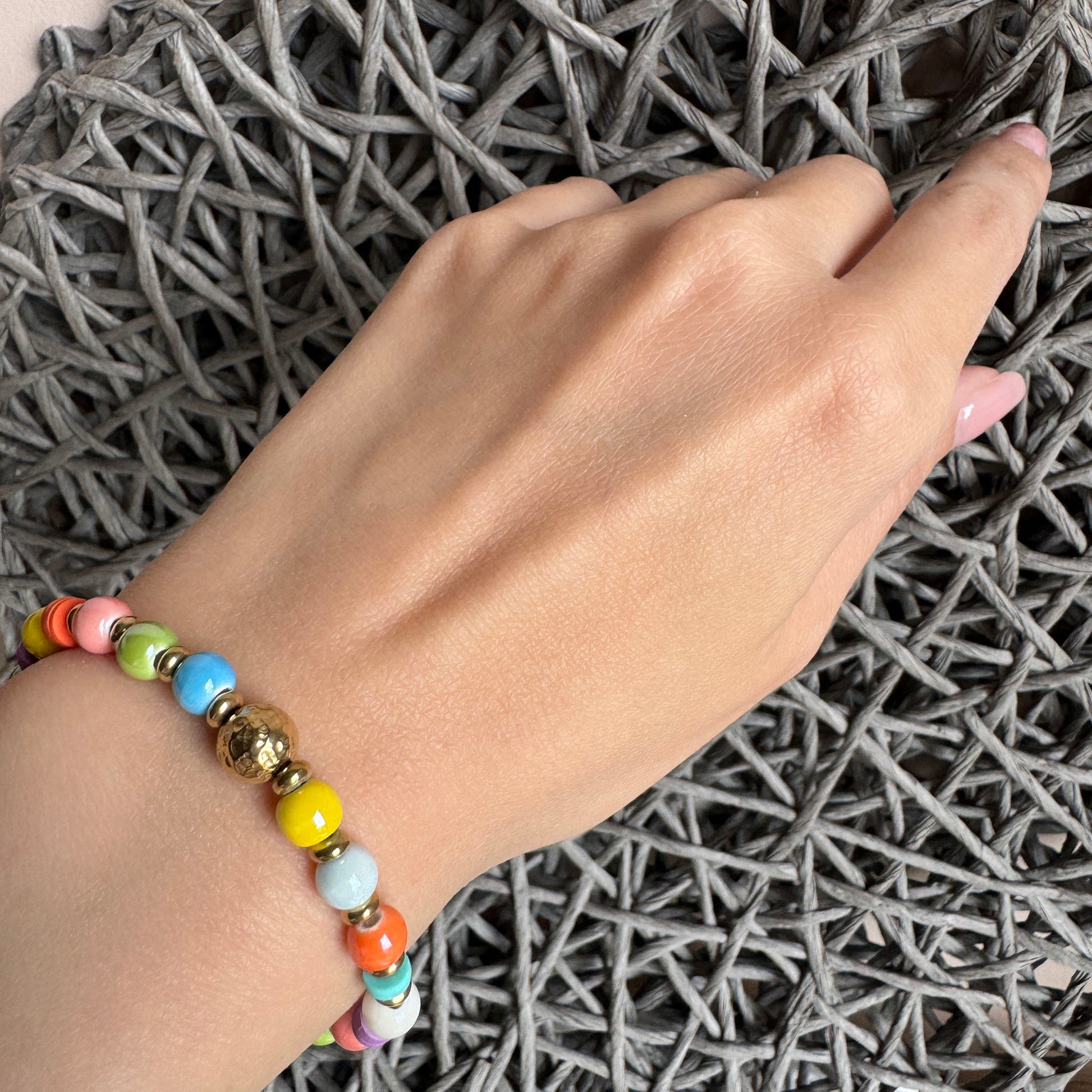 Boho-style bracelet with colorful ceramic beads and a gold hammered center ball, by Ikita.