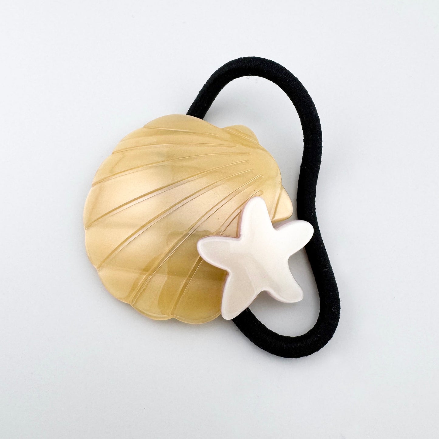 Haargummi mit Muschel und Seestern in goldigem Ton auf schwarzem Band
