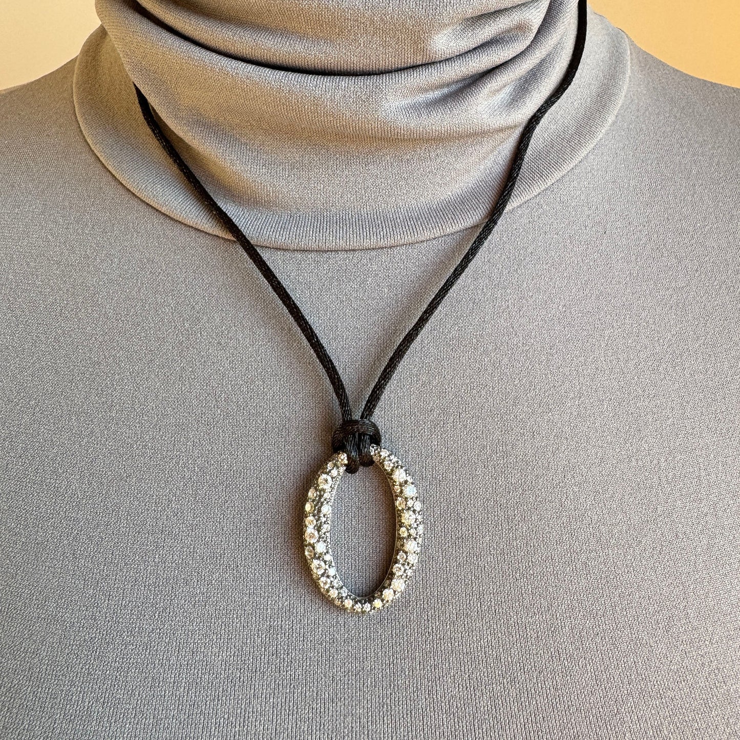 Oval zirconia necklace on a black cord, worn with a minimalist top