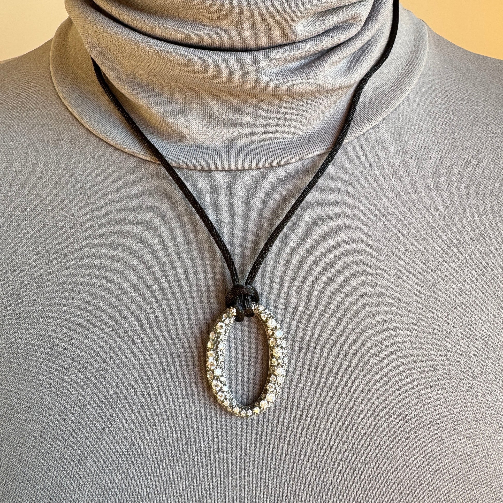 Oval zirconia necklace on a black cord, worn with a minimalist top