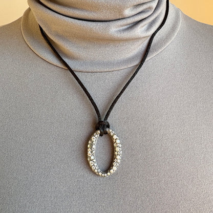 Oval zirconia necklace on a black cord, worn with a minimalist top