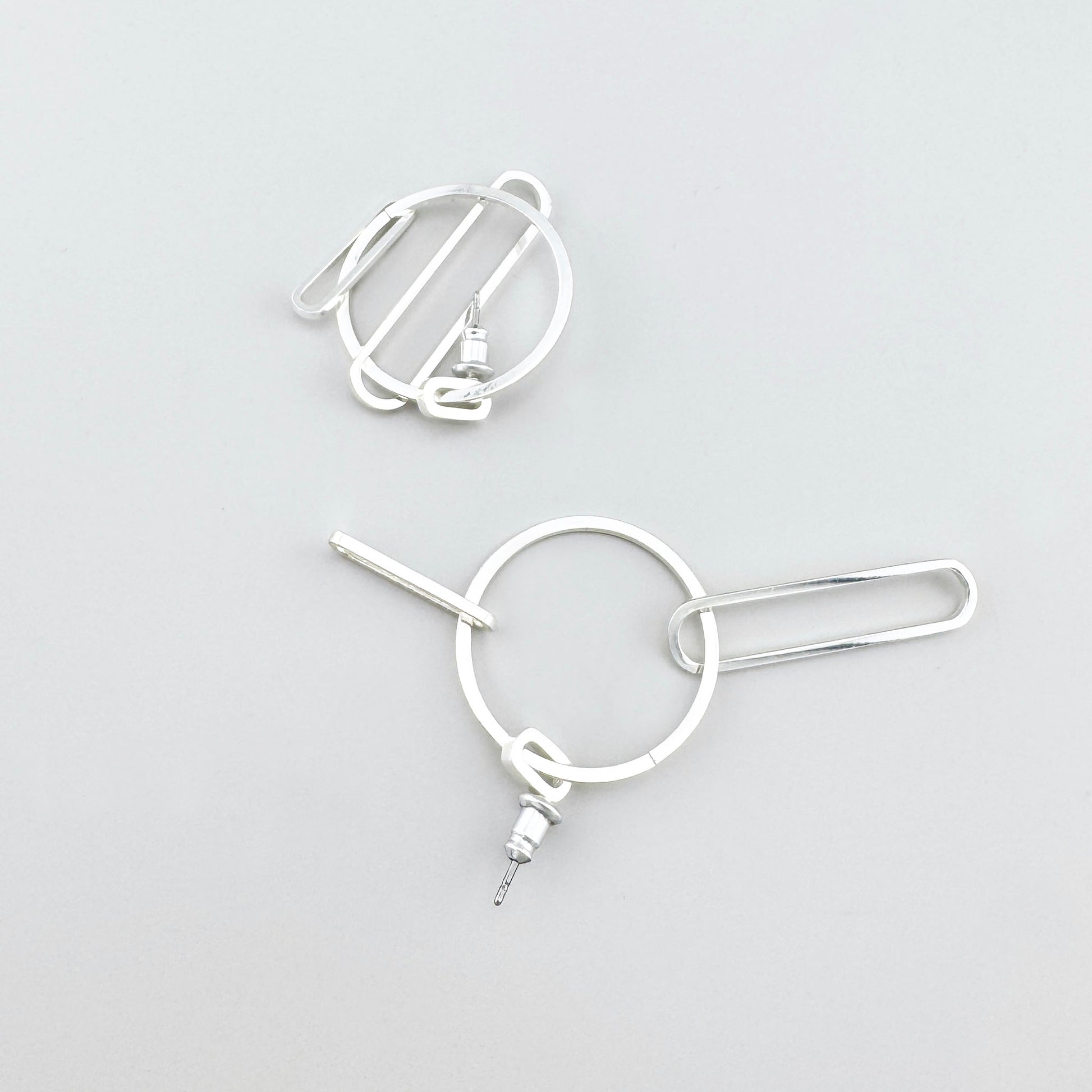 Pendientes geométricos Pilgrim con aro y barra tipo clip, brillo pulido y trazo industrial