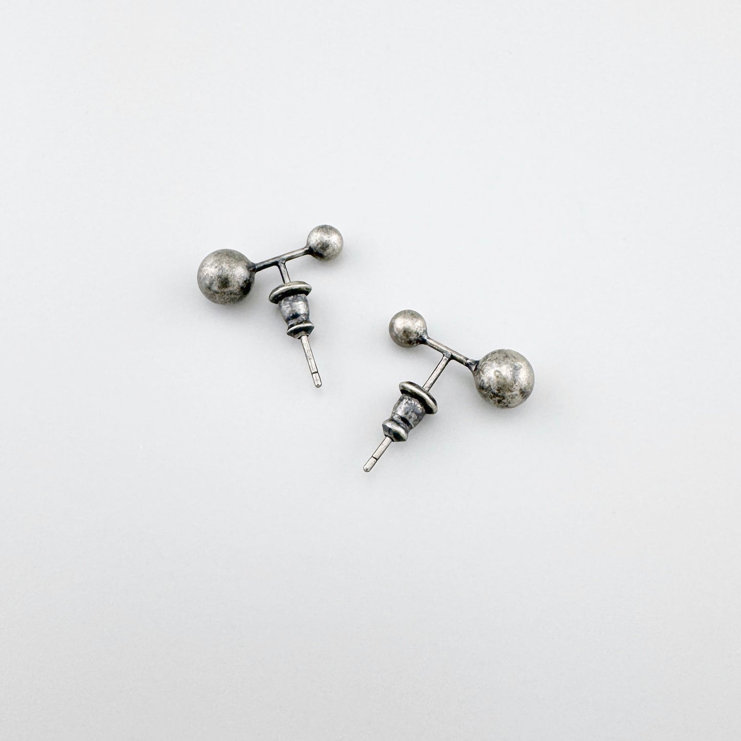 Srebrne kolczyki z patyną 925, dwie kulki różnej wielkości na białym tle, minimalistyczny styl