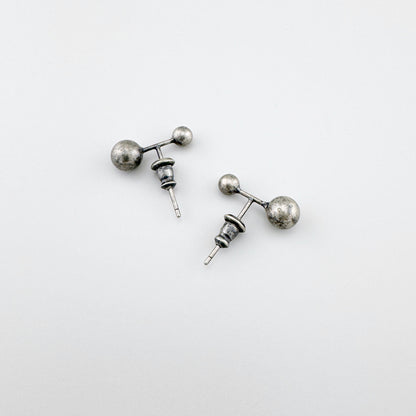 Srebrne kolczyki z patyną 925, dwie kulki różnej wielkości na białym tle, minimalistyczny styl