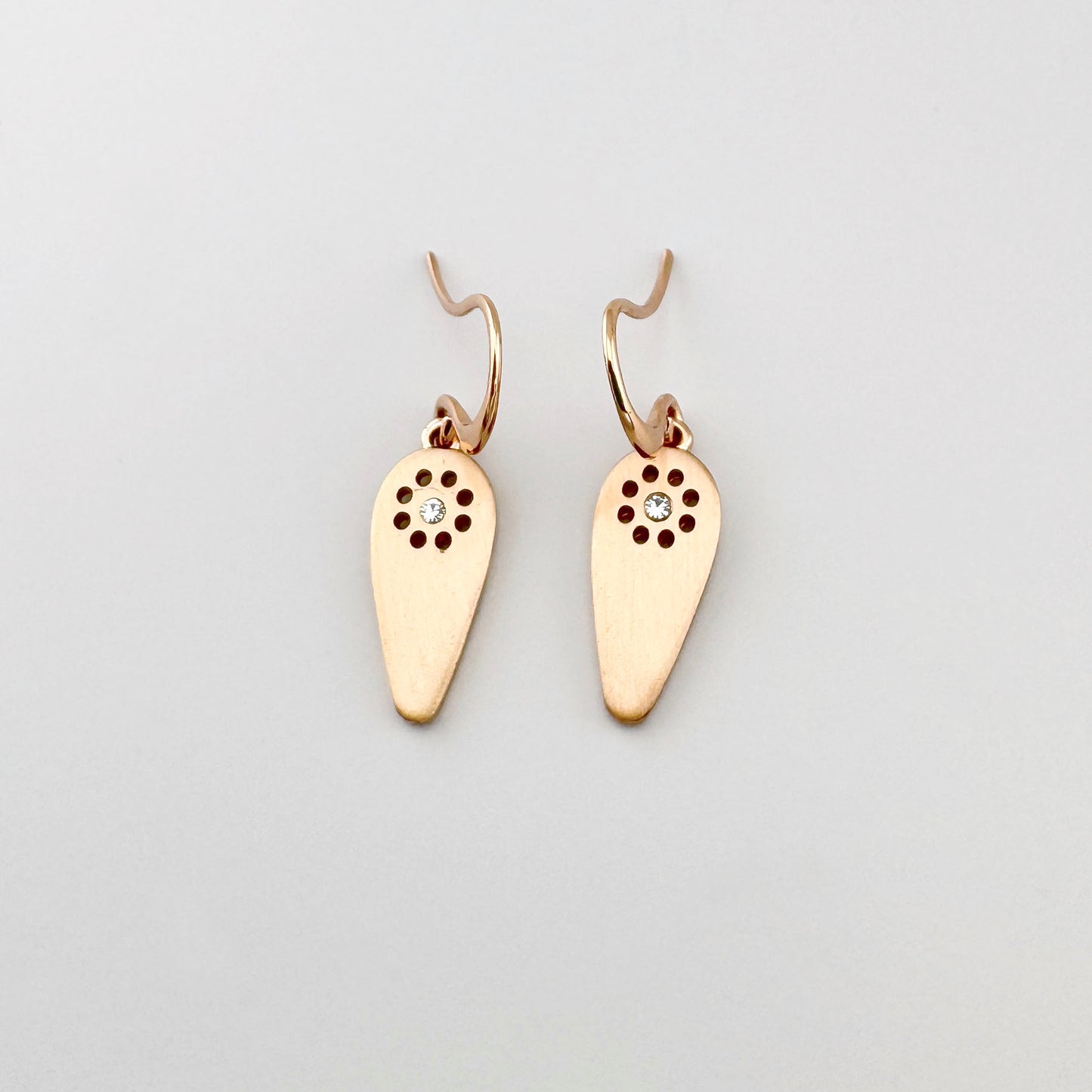 Kolczyki Pilgrim w odcieniu różowego złota z satynową kroplą i przejrzystym kryształem, lekki motyw słońca