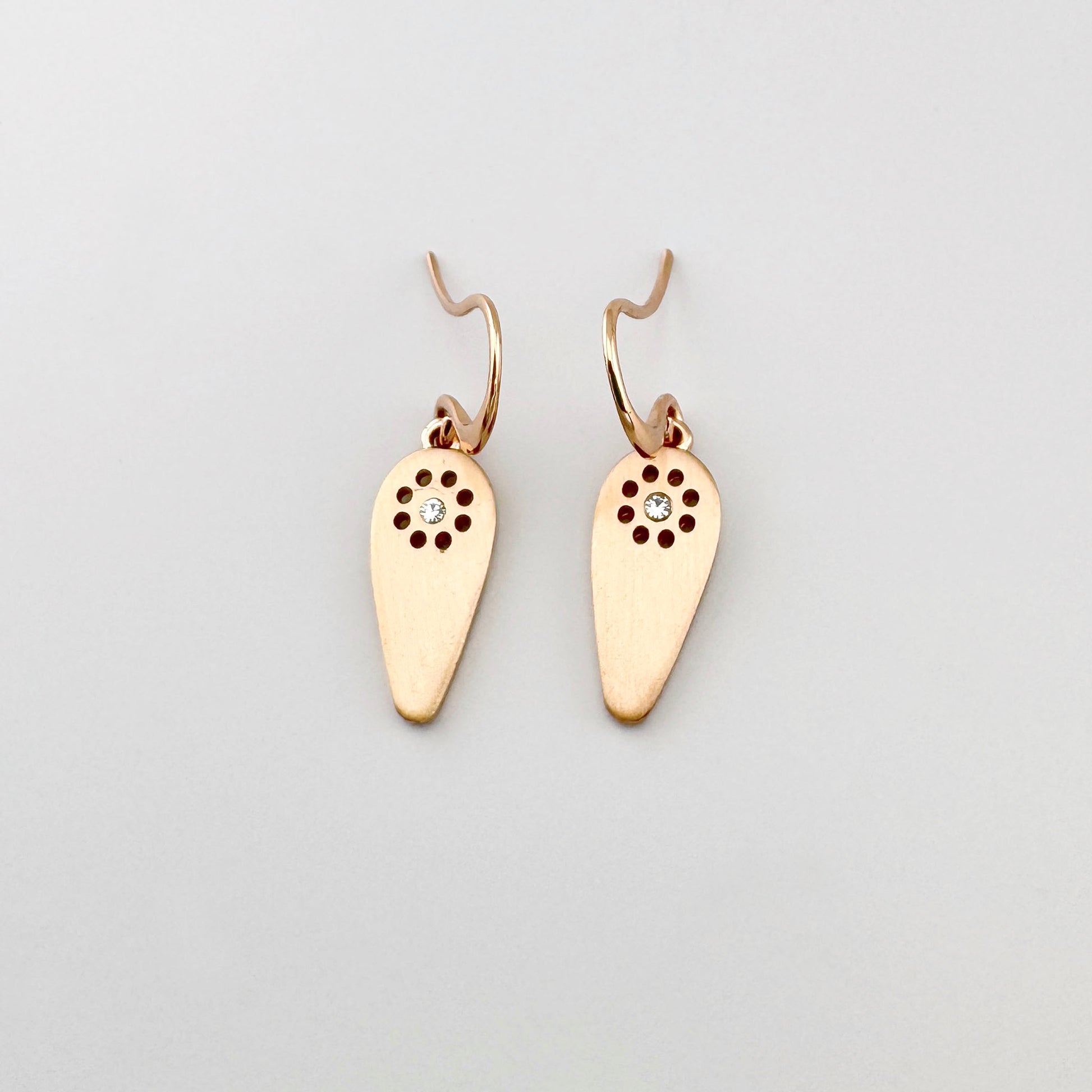 Kolczyki Pilgrim w odcieniu różowego złota z satynową kroplą i przejrzystym kryształem, lekki motyw słońca