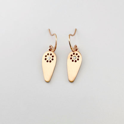 Kolczyki Pilgrim w odcieniu różowego złota z satynową kroplą i przejrzystym kryształem, lekki motyw słońca