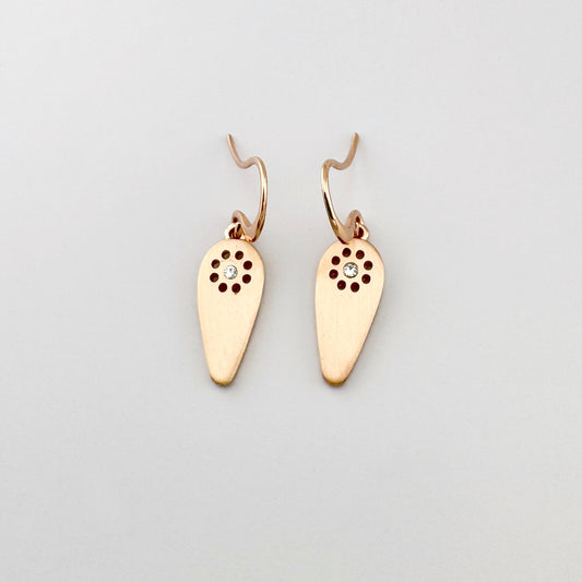 Kolczyki Pilgrim w odcieniu różowego złota z satynową kroplą i przejrzystym kryształem, lekki motyw słońca