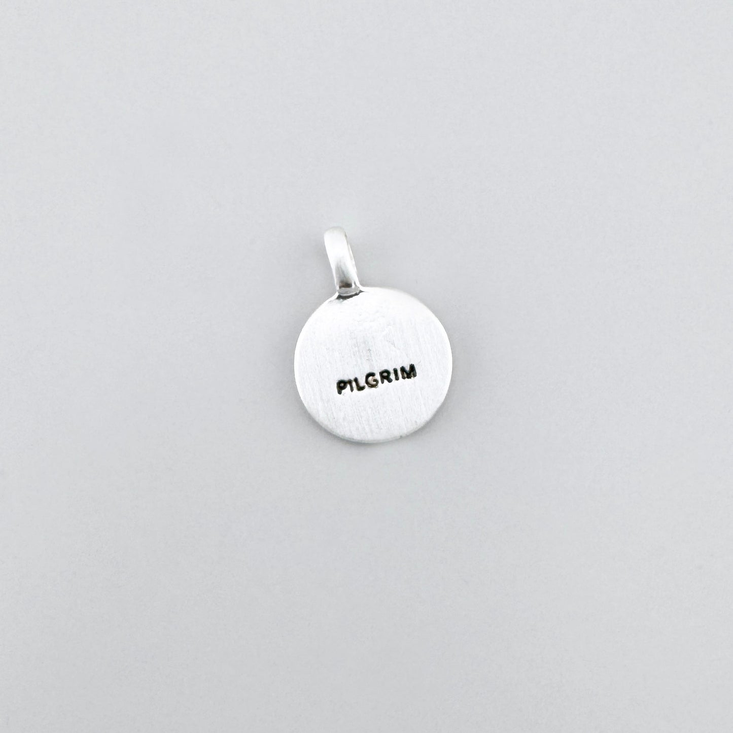 Pilgrim crystal pendant in silver tone showing the engraved back side