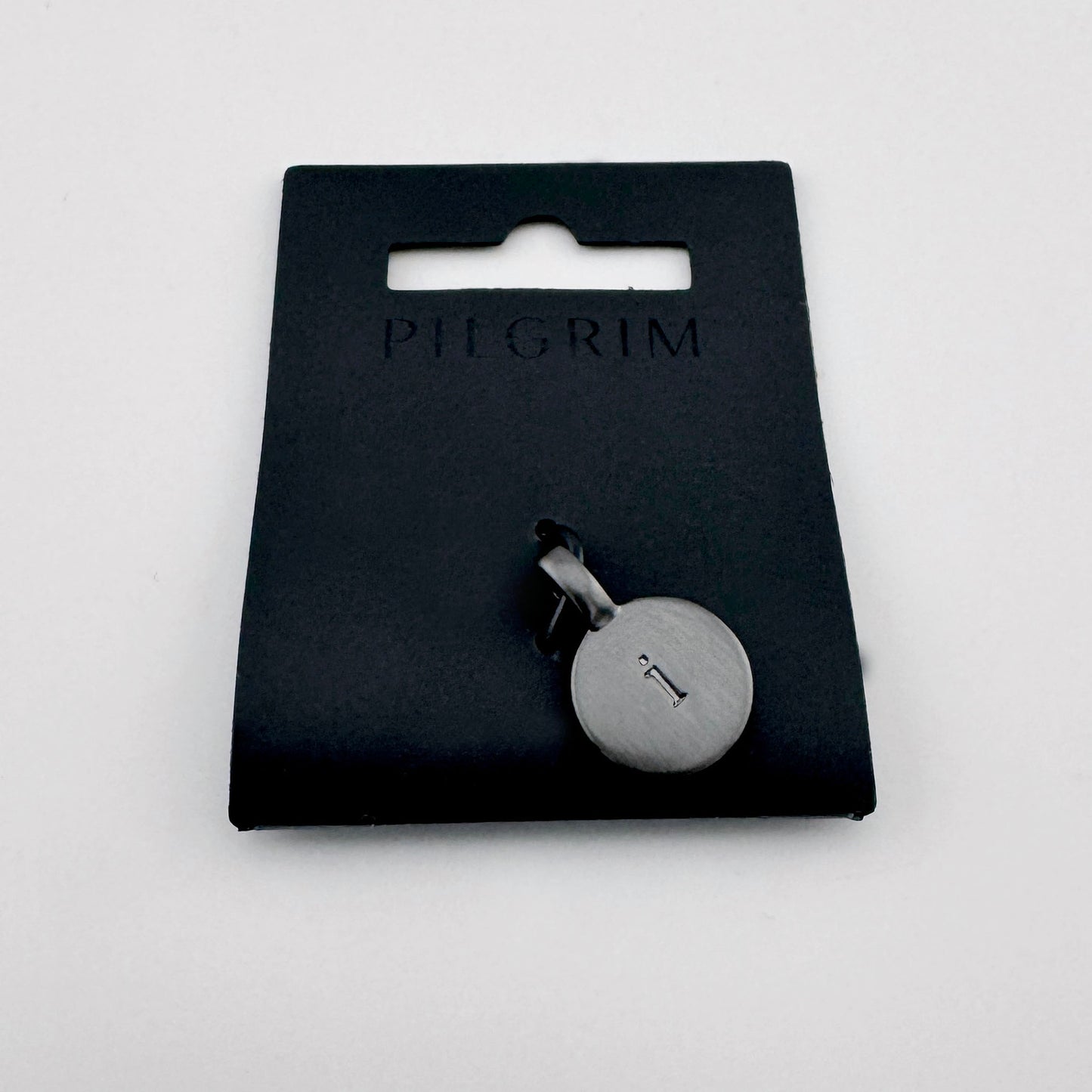Pilgrim letter I pendant in dark graphite tone on branded packaging