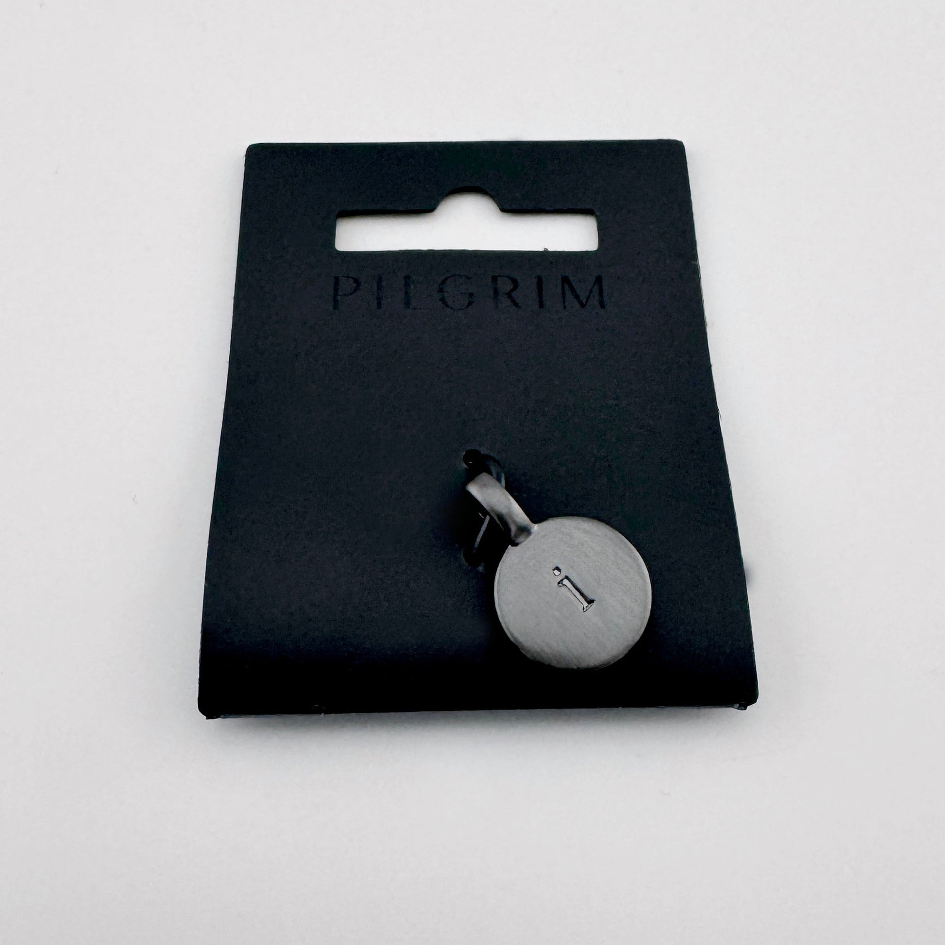 Pilgrim letter I pendant in dark graphite tone on branded packaging