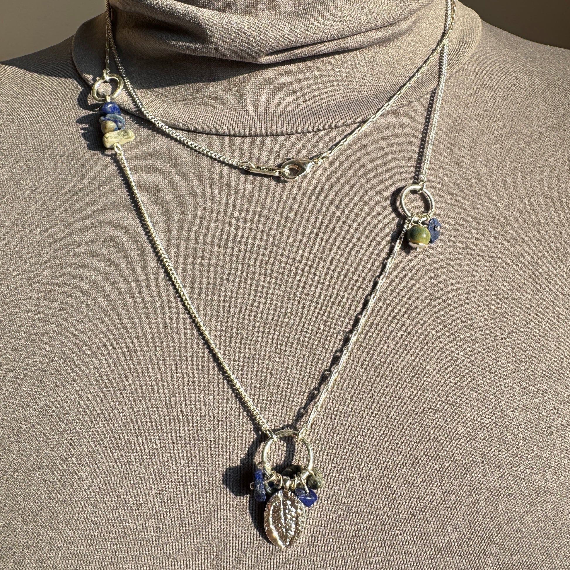 Pilgrim necklace with leaf charm and cobalt blue stones layered on mannequin