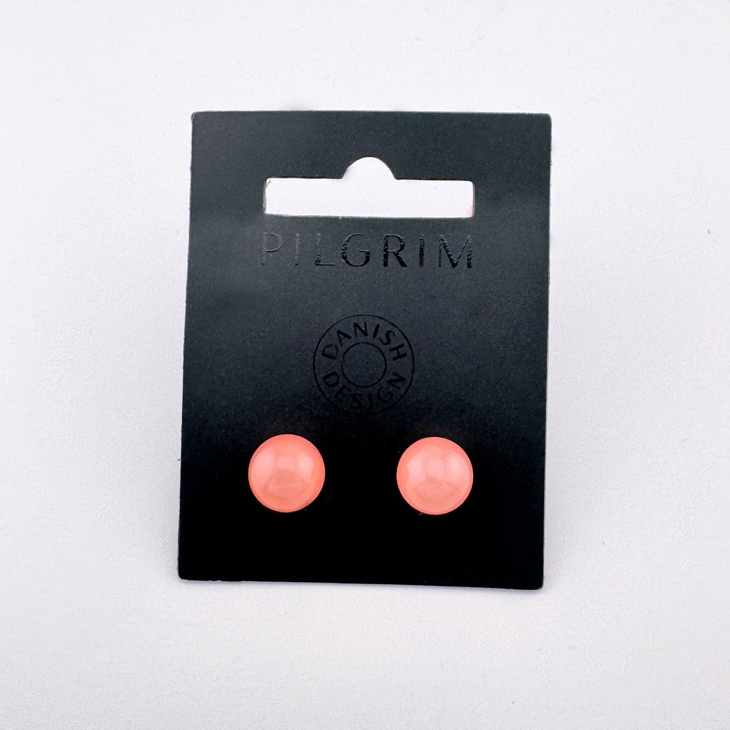 Clous boule rose Pilgrim au fini semi-translucide, contraste argenté, allure discrète et fraîche