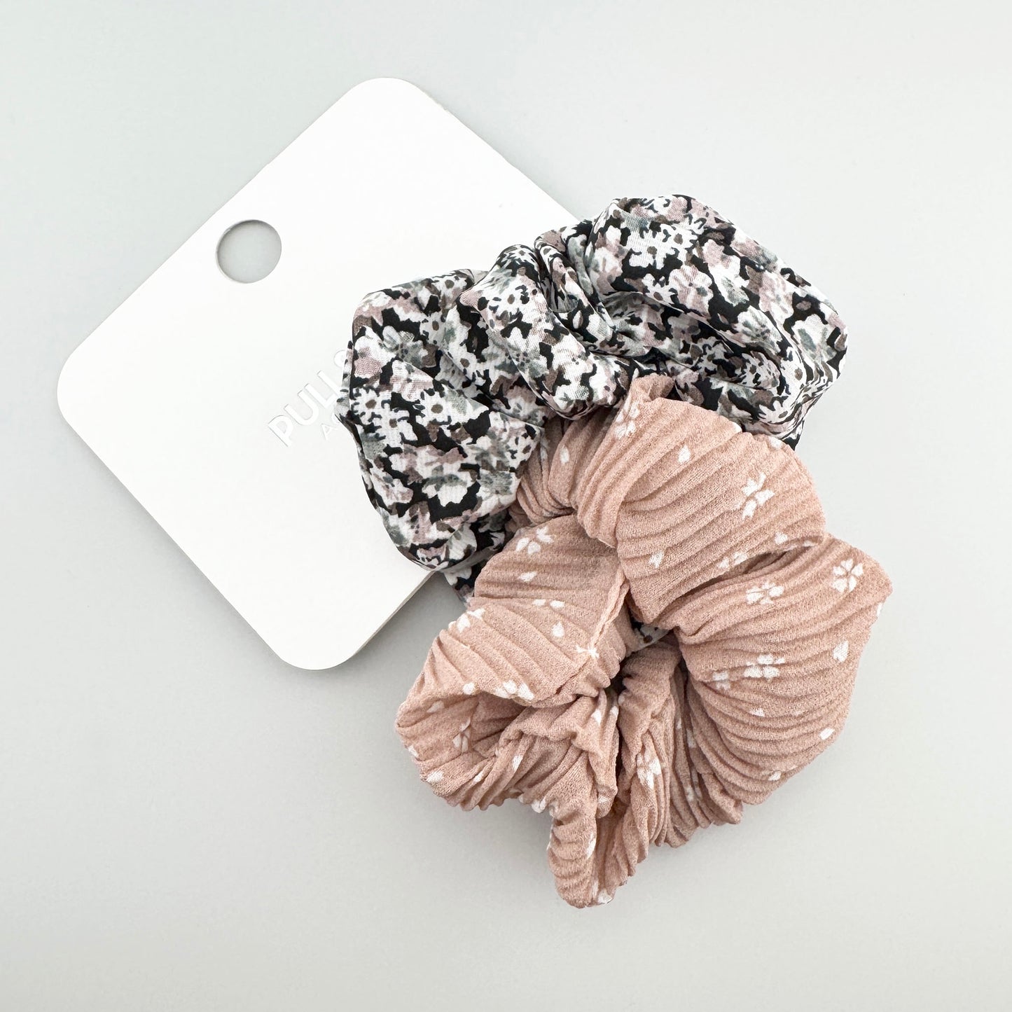 Pull&Bear beige and black floral scrunchies displayed together on a branded card
