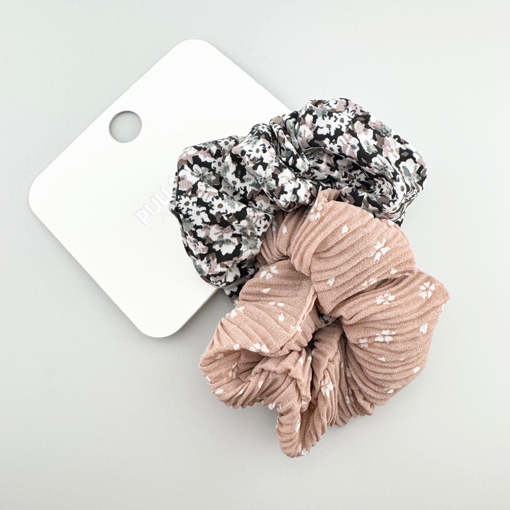 Pull&Bear beige and black floral scrunchies displayed together on a branded card
