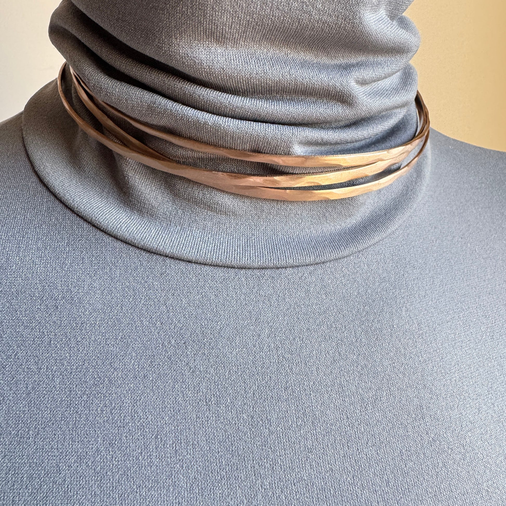 Rose gold open necklace worn close to the neck with a sculptural line