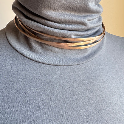 Rose gold open necklace worn close to the neck with a sculptural line