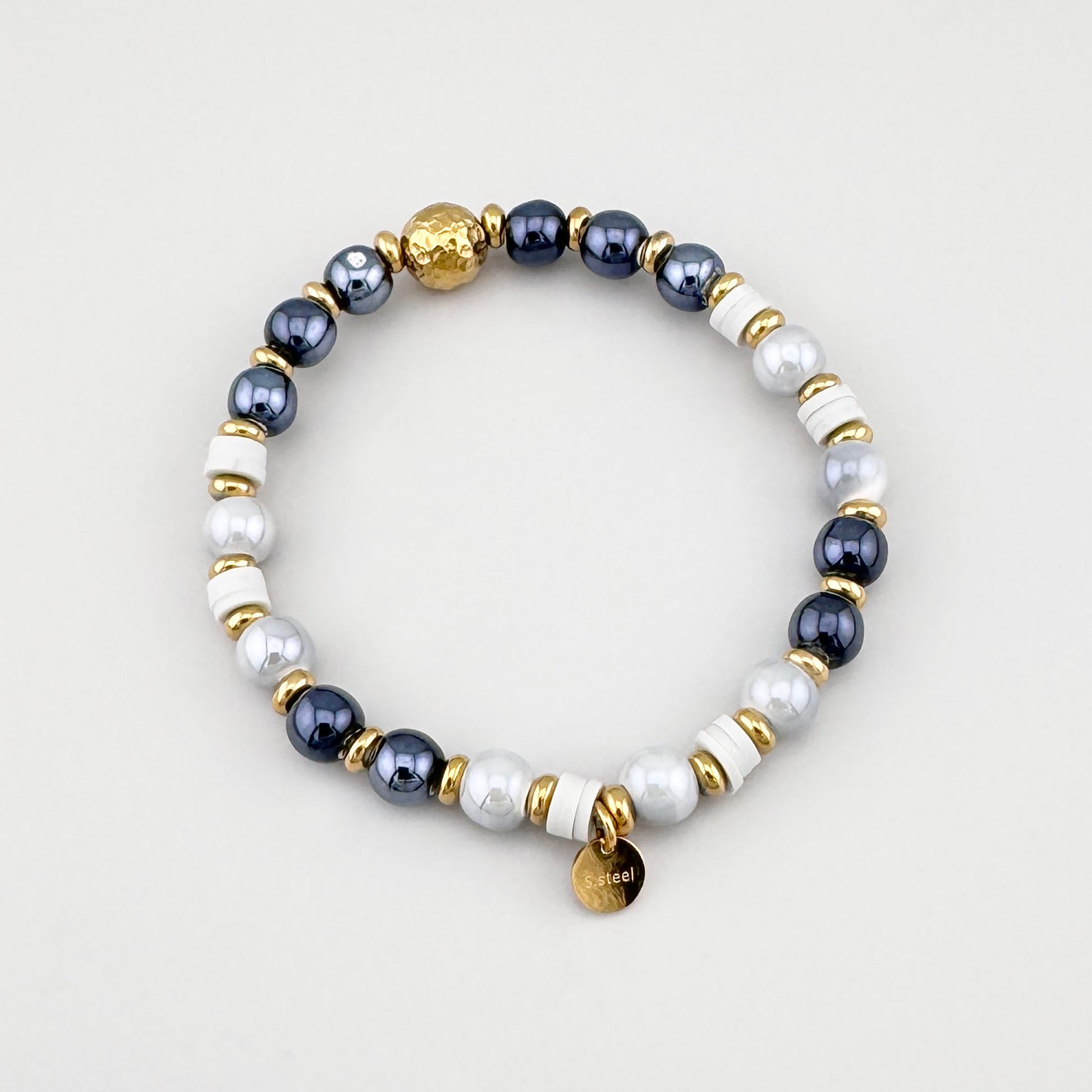 Pulsera con cuentas grises y blancas con detalles dorados dispuesta en círculo