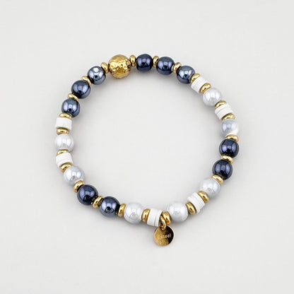Pulsera con cuentas grises y blancas con detalles dorados dispuesta en círculo