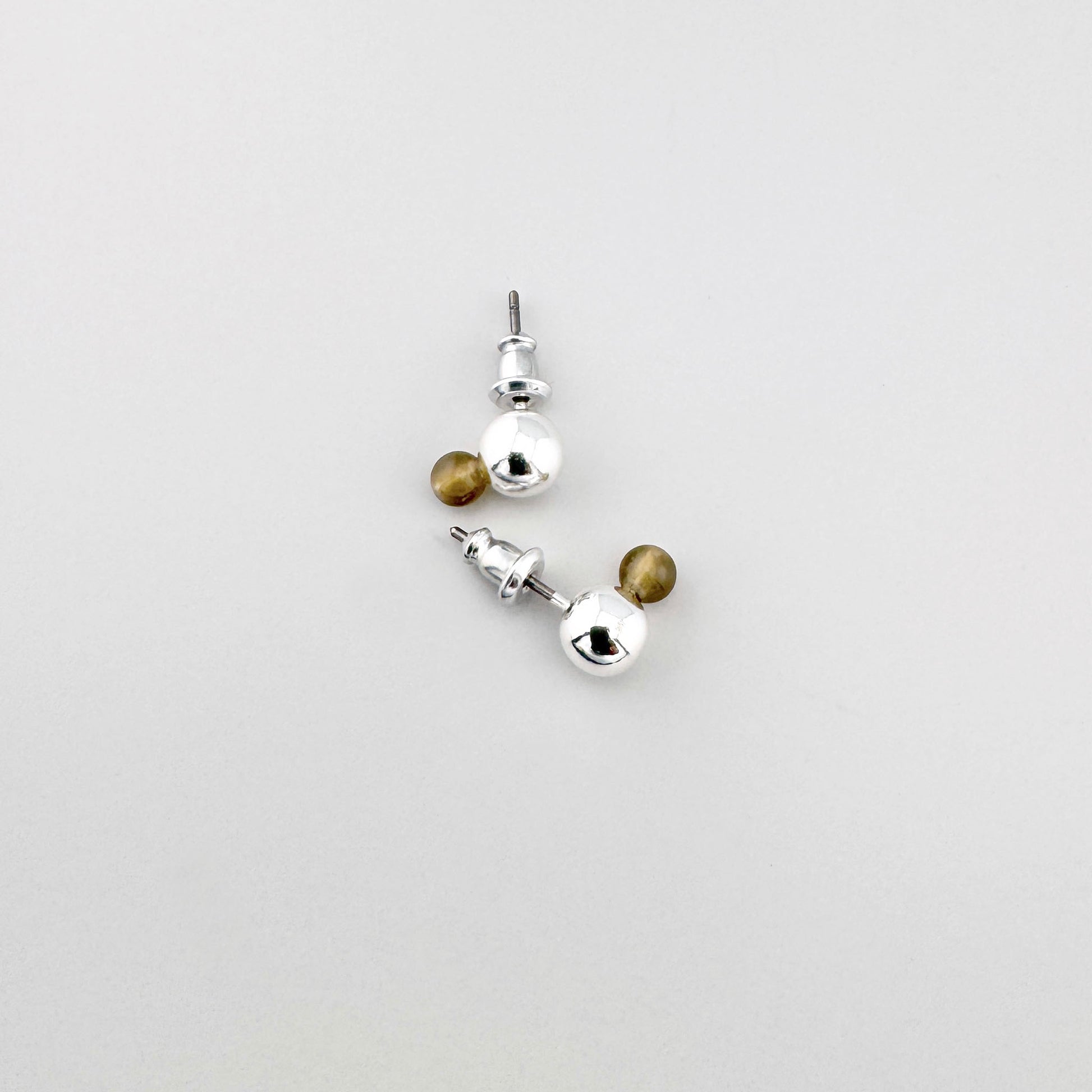 Pendientes tipo bola con frente plateado y trasera ámbar en diseño escandinavo
