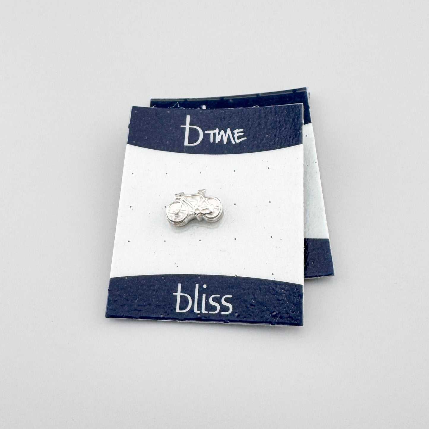 Silver bicycle charm Bliss Gioielli displayed on two overlapping branded cards
