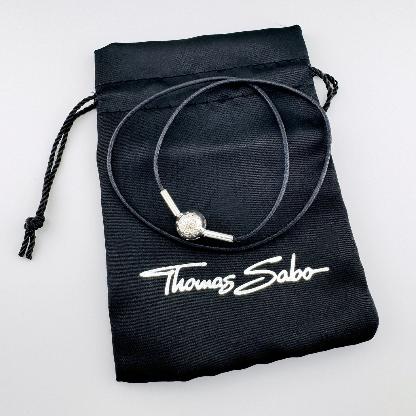 Black cord choker by Thomas Sabo with a silver compass bead displayed on a branded pouch