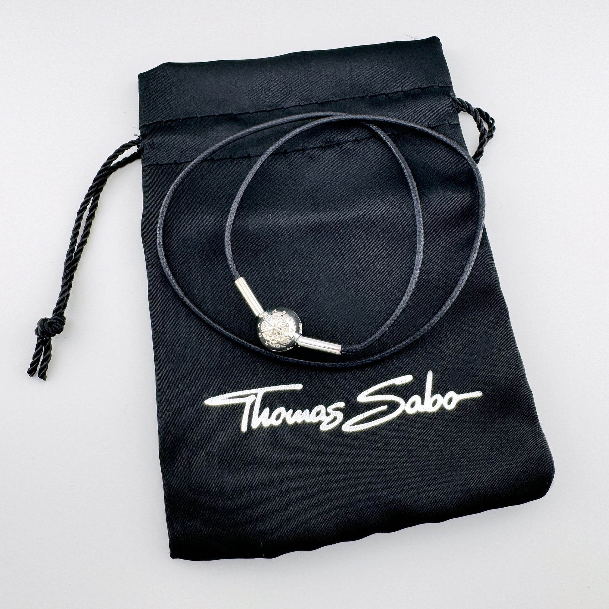 Black cord choker by Thomas Sabo with a silver compass bead displayed on a branded pouch