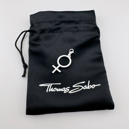 Silberner Thomas Sabo Charm mit Frauensymbol auf dem schwarzen Markenbeutel