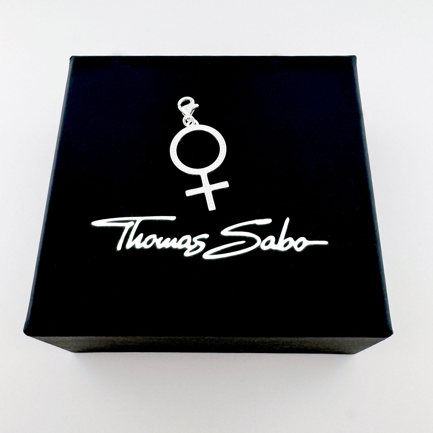 Silberner Frauen-Symbol-Charm von Thomas Sabo auf einer schwarzen Markenbox