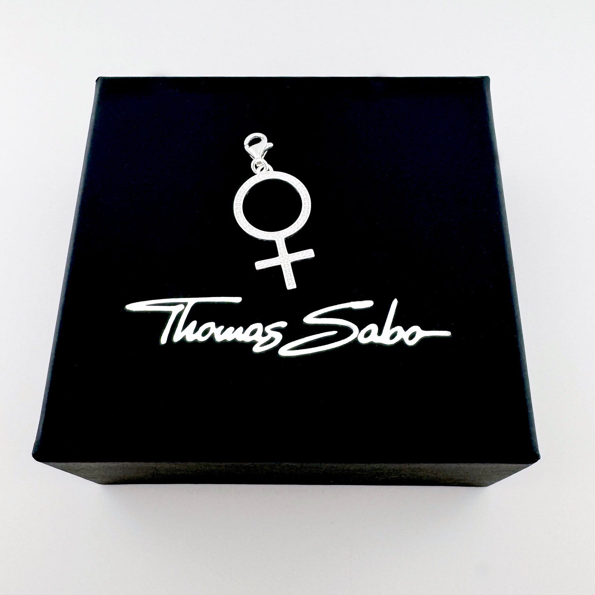 Silberner Frauen-Symbol-Charm von Thomas Sabo auf einer schwarzen Markenbox