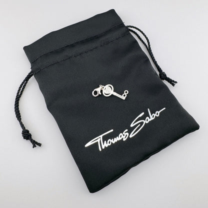 Silver Thomas Sabo key charm displayed on its branded black pouch
