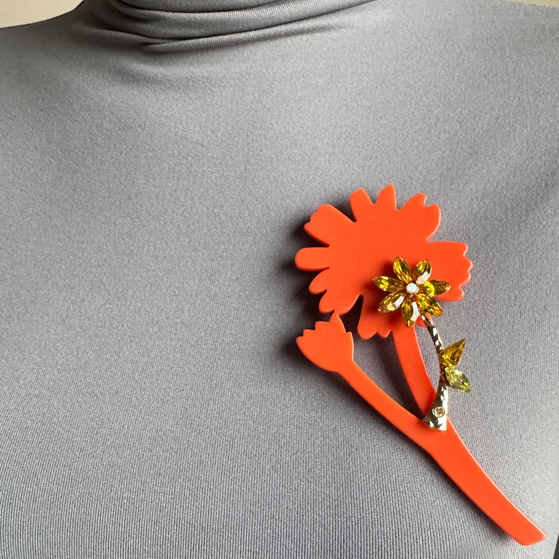Orange flower crystal brooch by Sonata pinned to clothing for a bright accent