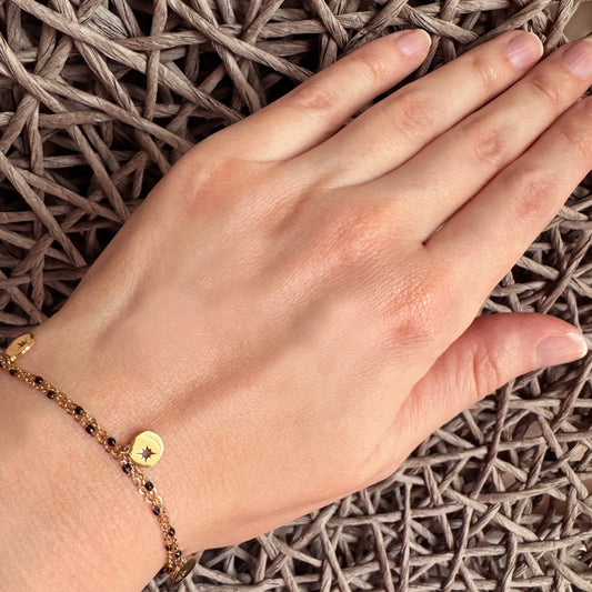 Gold star charm bracelet IRL worn on the wrist with layered delicate chains