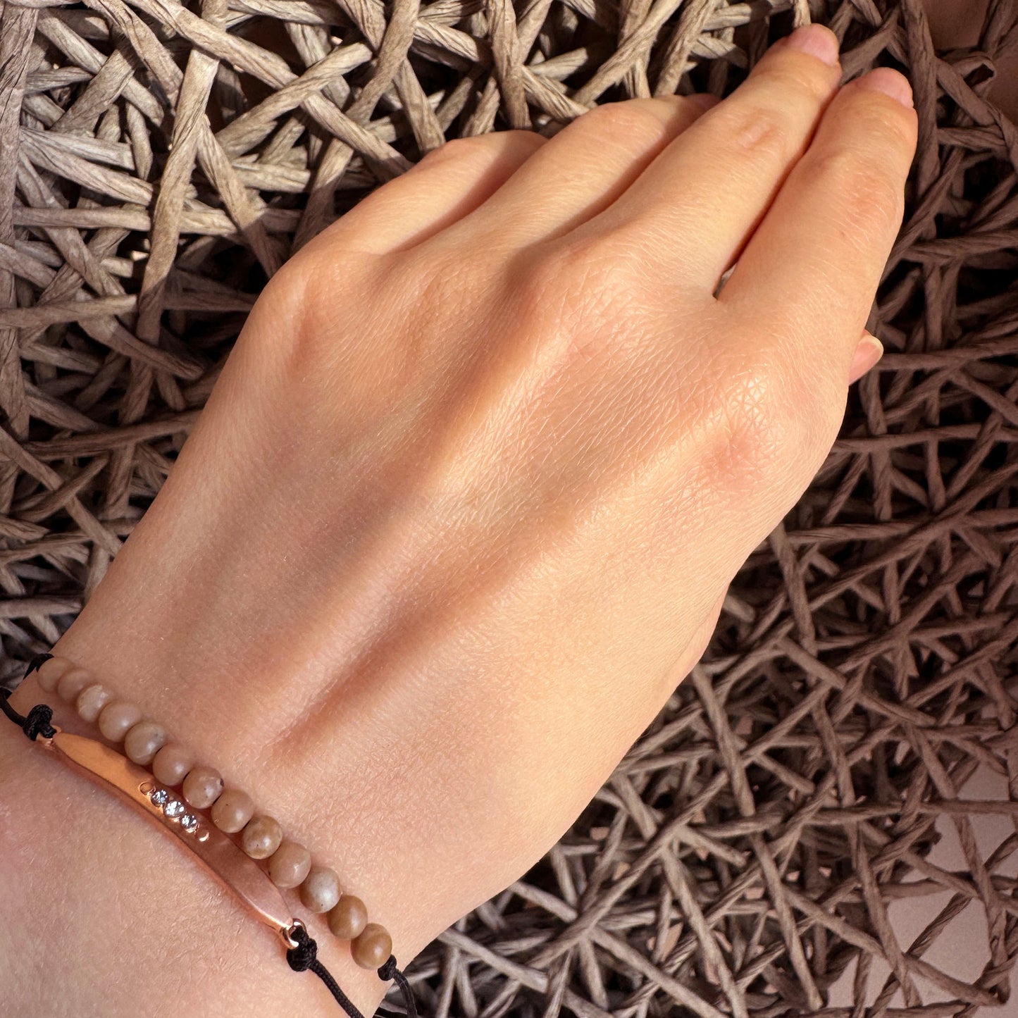 Natural stone bracelet worn on the wrist with subtle rose gold detail and black cord