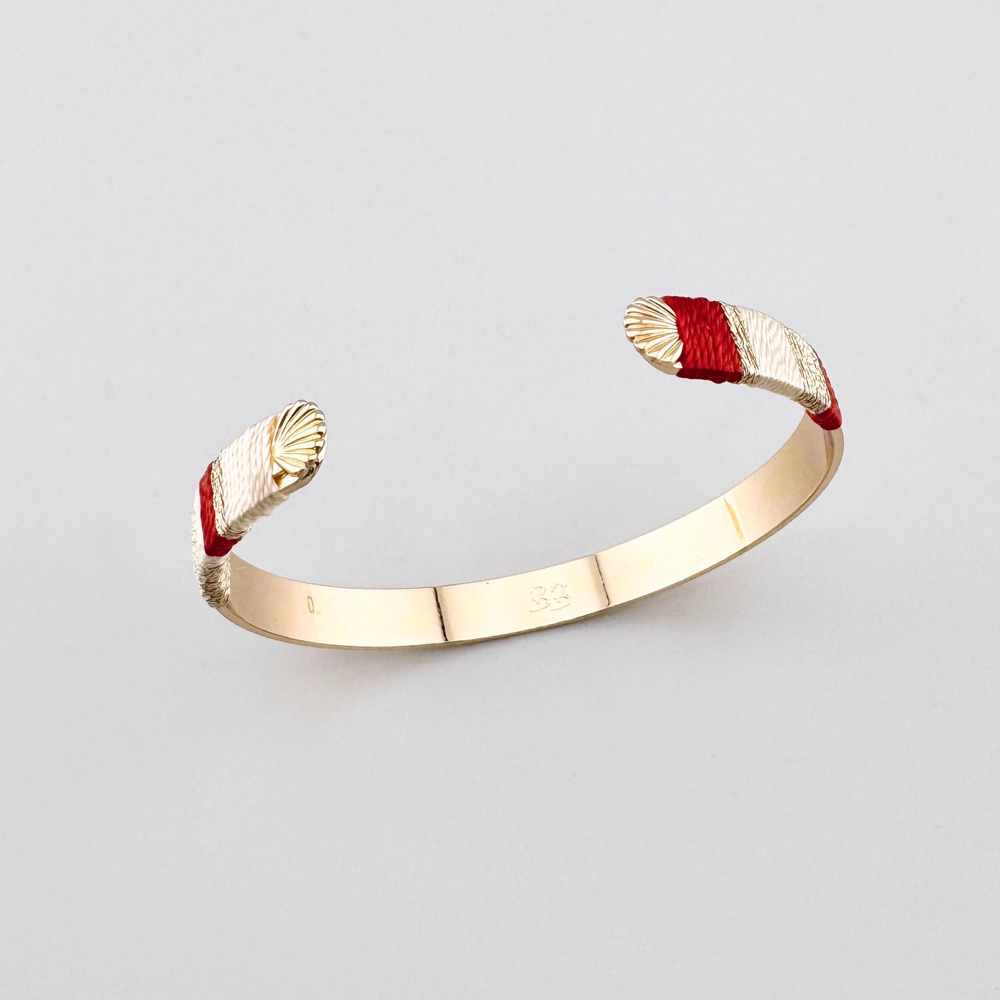 Pulsera Sonata con extremos envueltos en hilo y forma abierta dorada