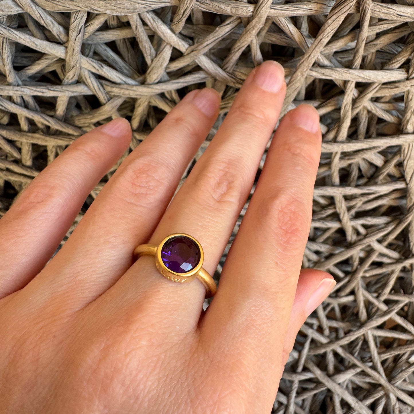 Violet quartz ring worn on hand with warm gold-tone finish