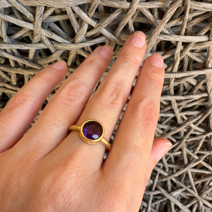 Violet quartz ring worn on hand with warm gold-tone finish