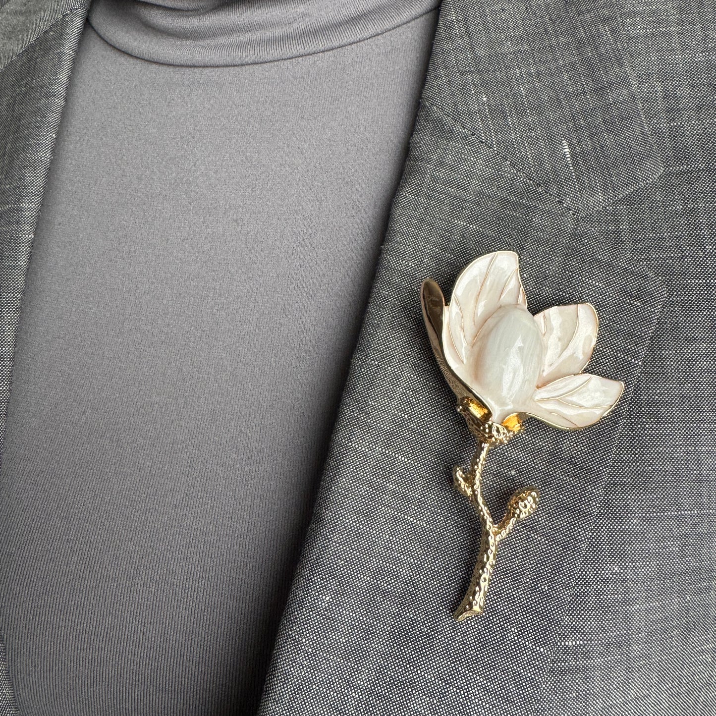 White enamel flower brooch Sonata worn on a blazer with a gold-tone stem