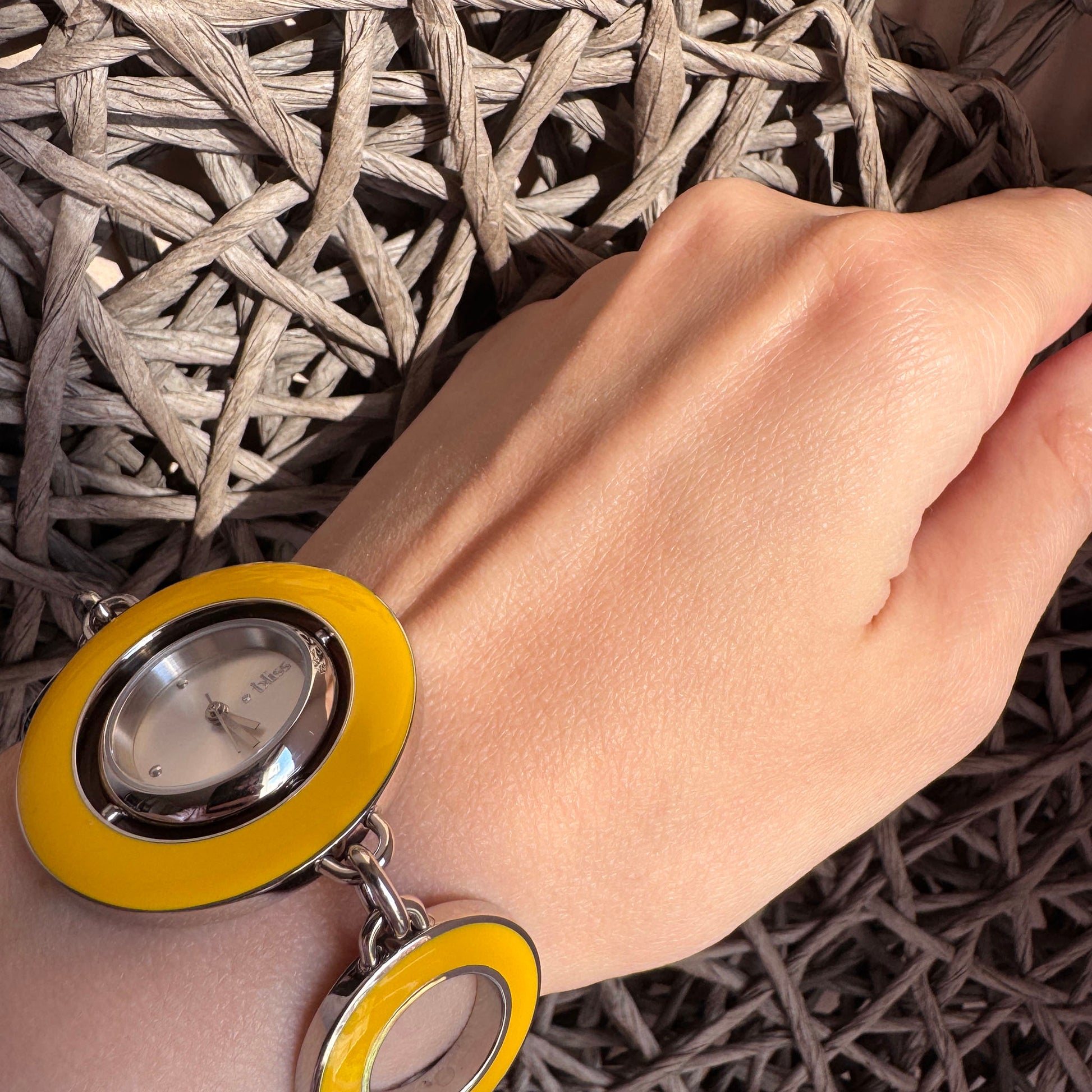 Reversible bracelet watch worn on wrist showing yellow enamel side