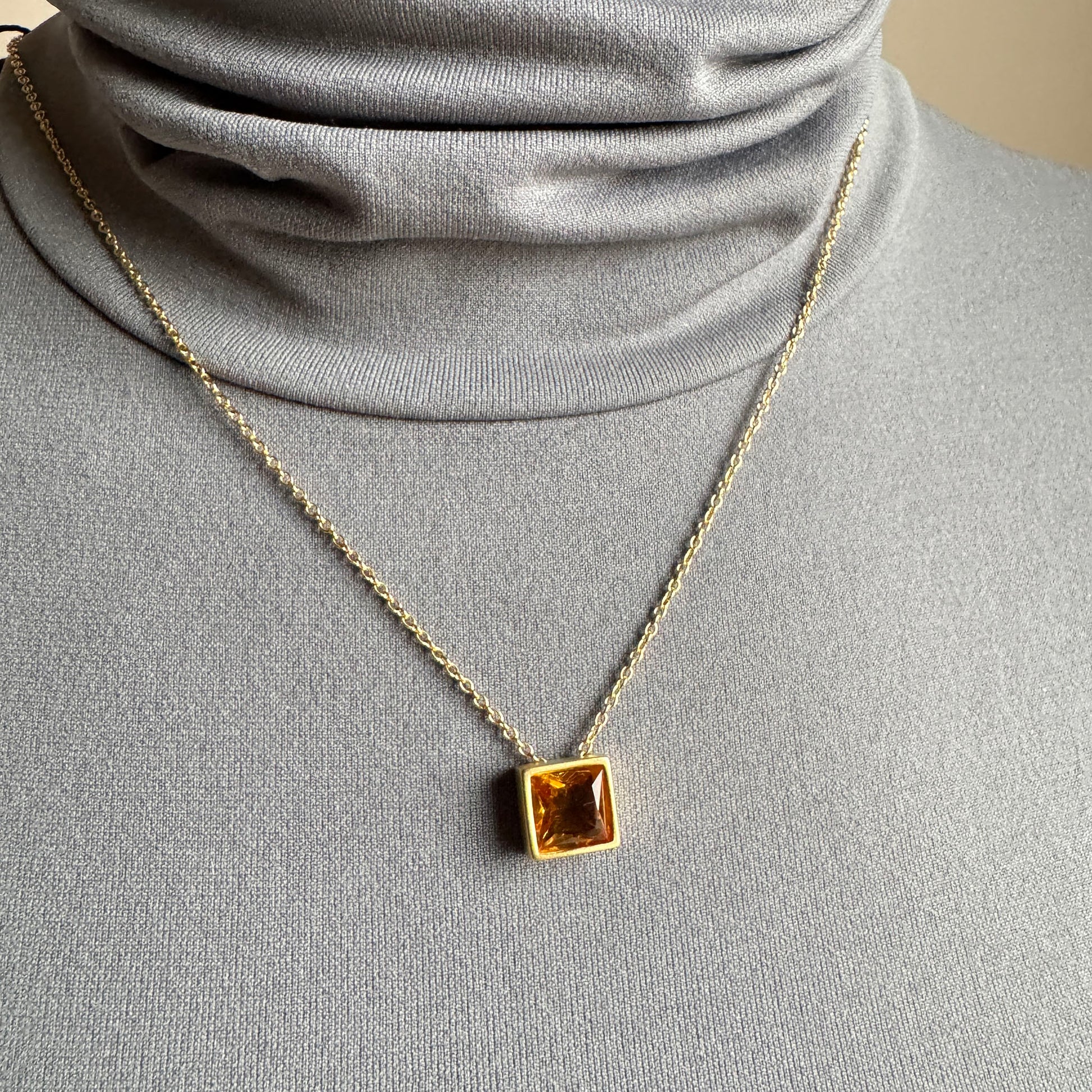 Yellow quartz pendant necklace worn at the neckline on a delicate chain