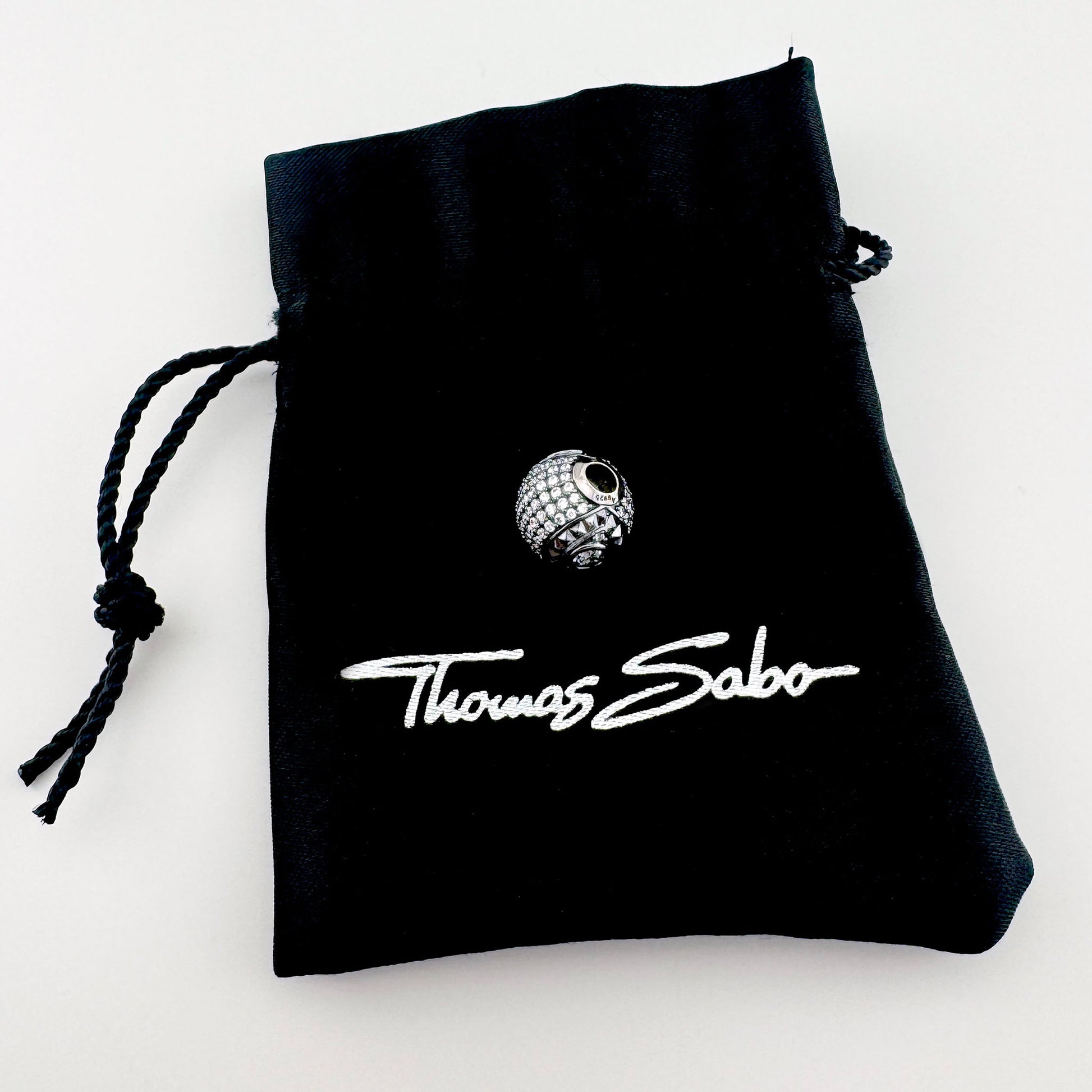 Silver zirconia charm Thomas Sabo displayed with a black branded pouch
