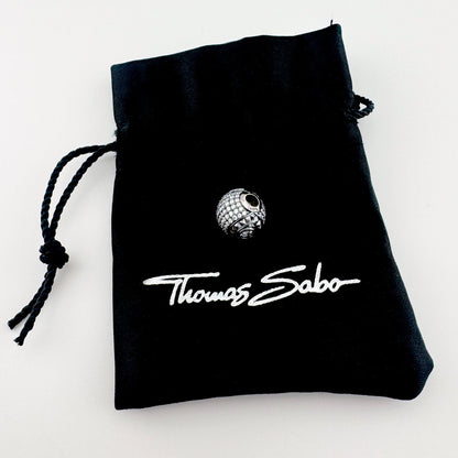 Silver zirconia charm Thomas Sabo displayed with a black branded pouch
